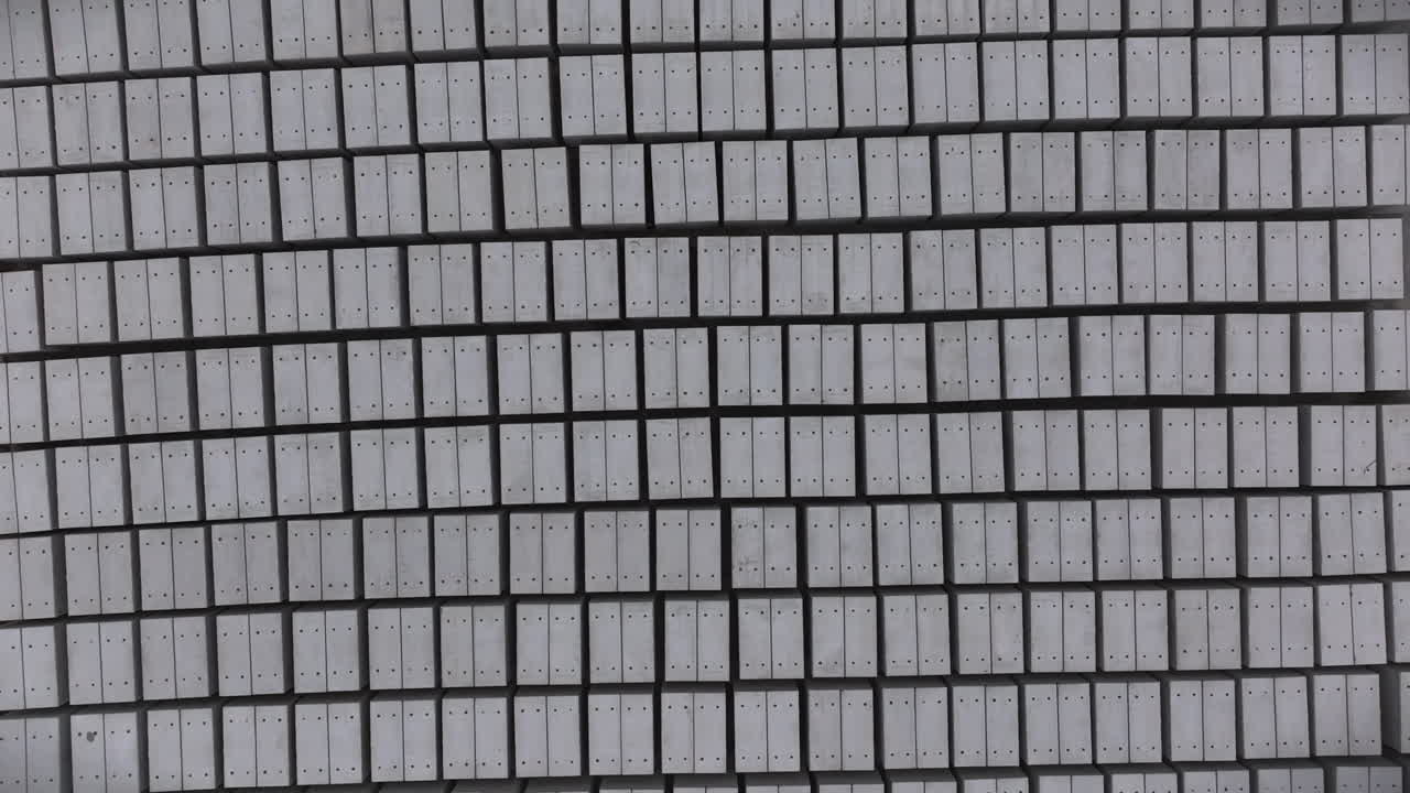 Top-down Aerial View of precision-engineered grid of uniform gray rectangular concrete panels, meticulously aligned in a systematic pattern with subtle depth and architectural symmetry.