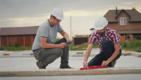 Two-Builders-Check-The-Accuracy-Of-Building-The-Base-Of-The-Building-Conduct-Records-In-The-Tablet-4