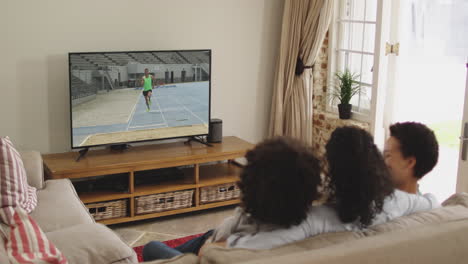 composite of happy family sitting at home together watching long jump athletics on tv