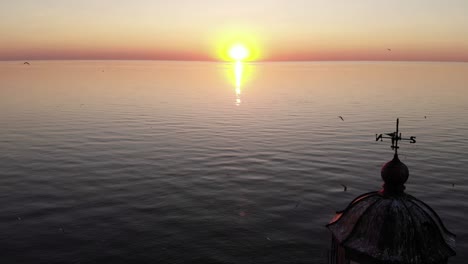 sunset at large lake, aerial camera fly back and show old lighthouse at isle