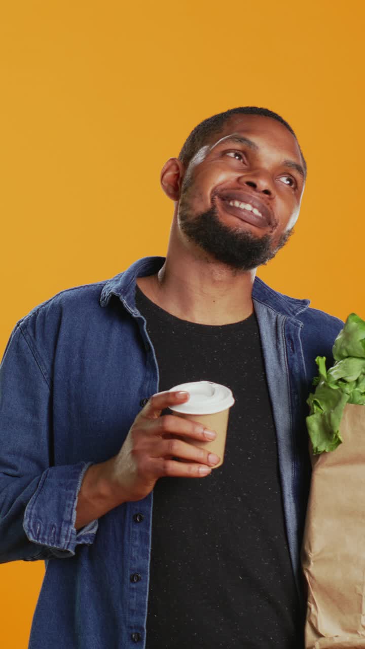 Happy Young Man Drinking Coffee and Holding Groceries