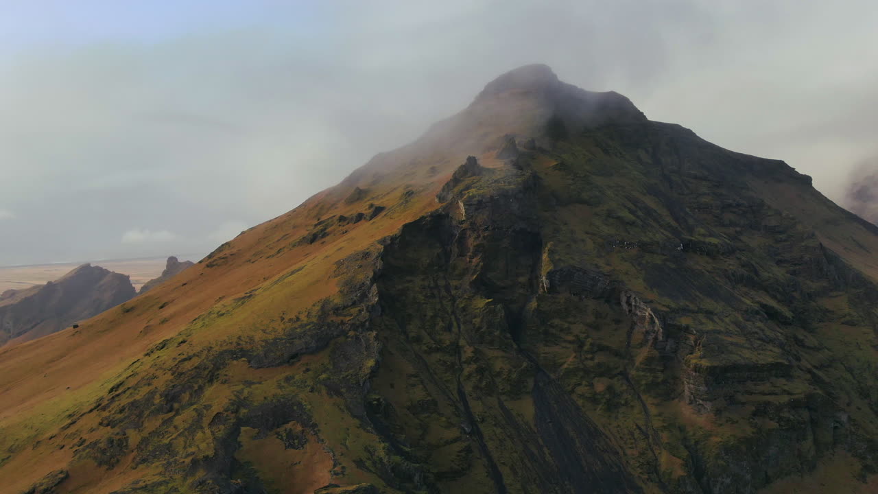 avión no tripulado cinematográfico hacia adelante al movimiento derecho de la montaña cerca de skogafoss cascada de islandia con pájaros y nubes tarde luz del sol