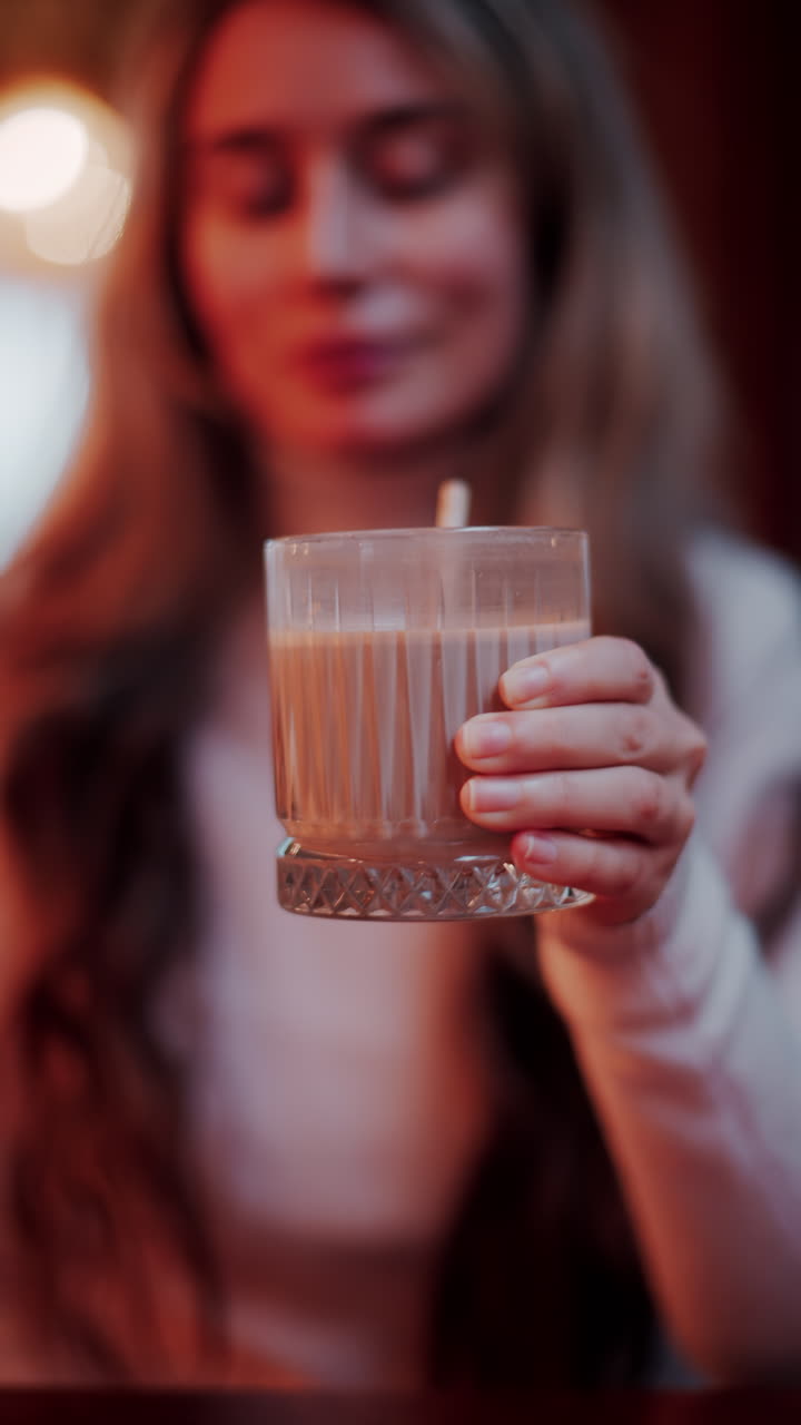 Close up of a woman drinking hot chocolate with a straw at a cafe. Vertical