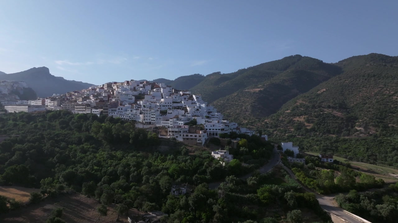 Veduta aerea con drone di Moulay Idriss Zerhoun, adagiata sulle pendici dei Monti Zerhoun nel Marocco settentrionale, circondata da uliveti, valli verdi e un paesaggio rurale pittoresco