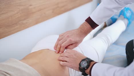 physiotherapist checks the back of a patient. woman is lying on bed and doctor expertises female's spine in clinic. close-up.