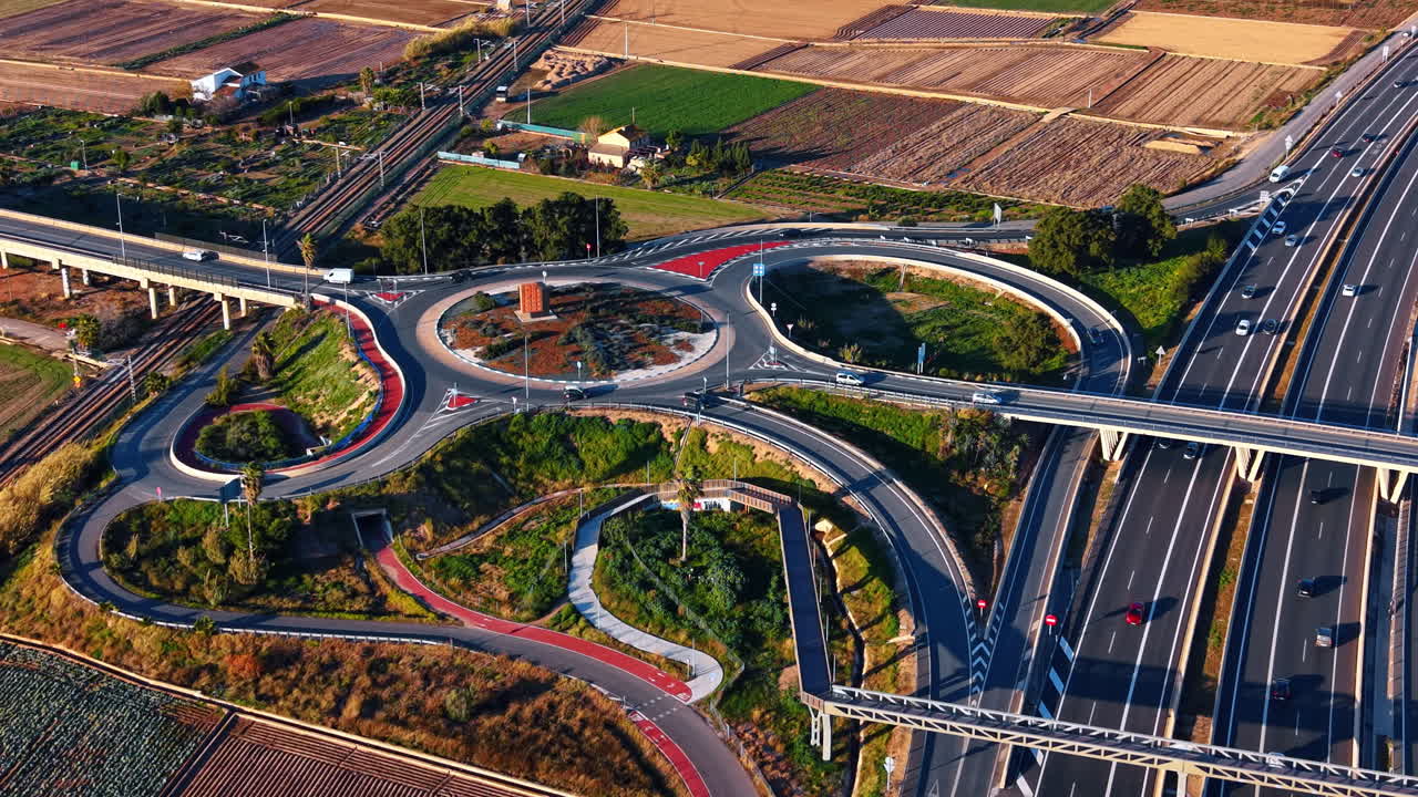 Complex road roundabout and highway interchange. Wide drone shot of a circular road junction with bicycle paths and green fields in Valencia