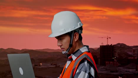 ingeniero trabajando en una computadora portátil en un sitio de construcción al atardecer