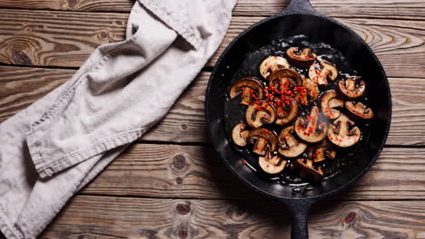 sautéed mushrooms with chili flakes in a cast iron skillet on a wooden table