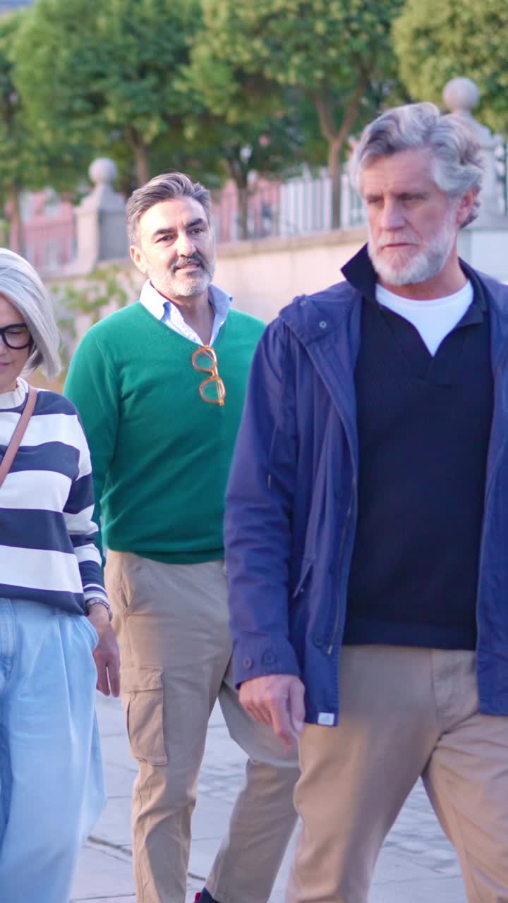 Grupo de amigos de meia-idade e idosos caminhando e conversando ao ar livre