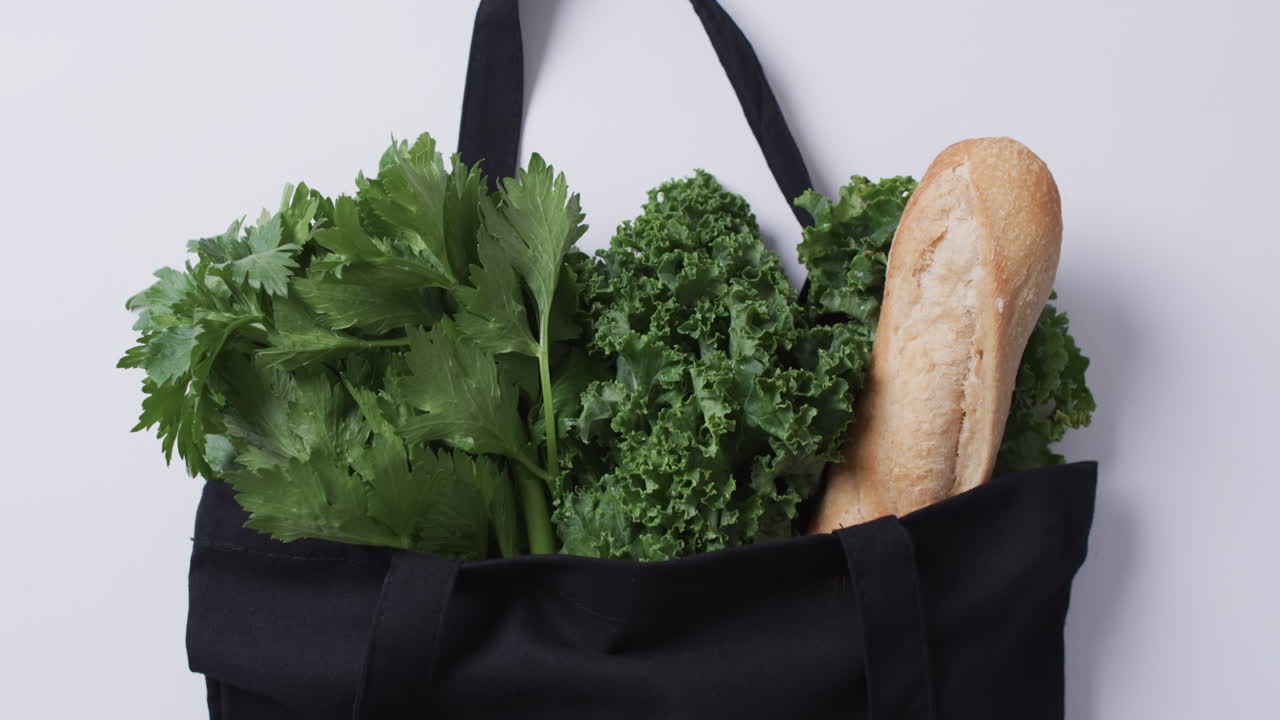 Video di borsa di tela nera con prezzemolo, cavolo riccio e baguette, spazio per il testo su sfondo bianco