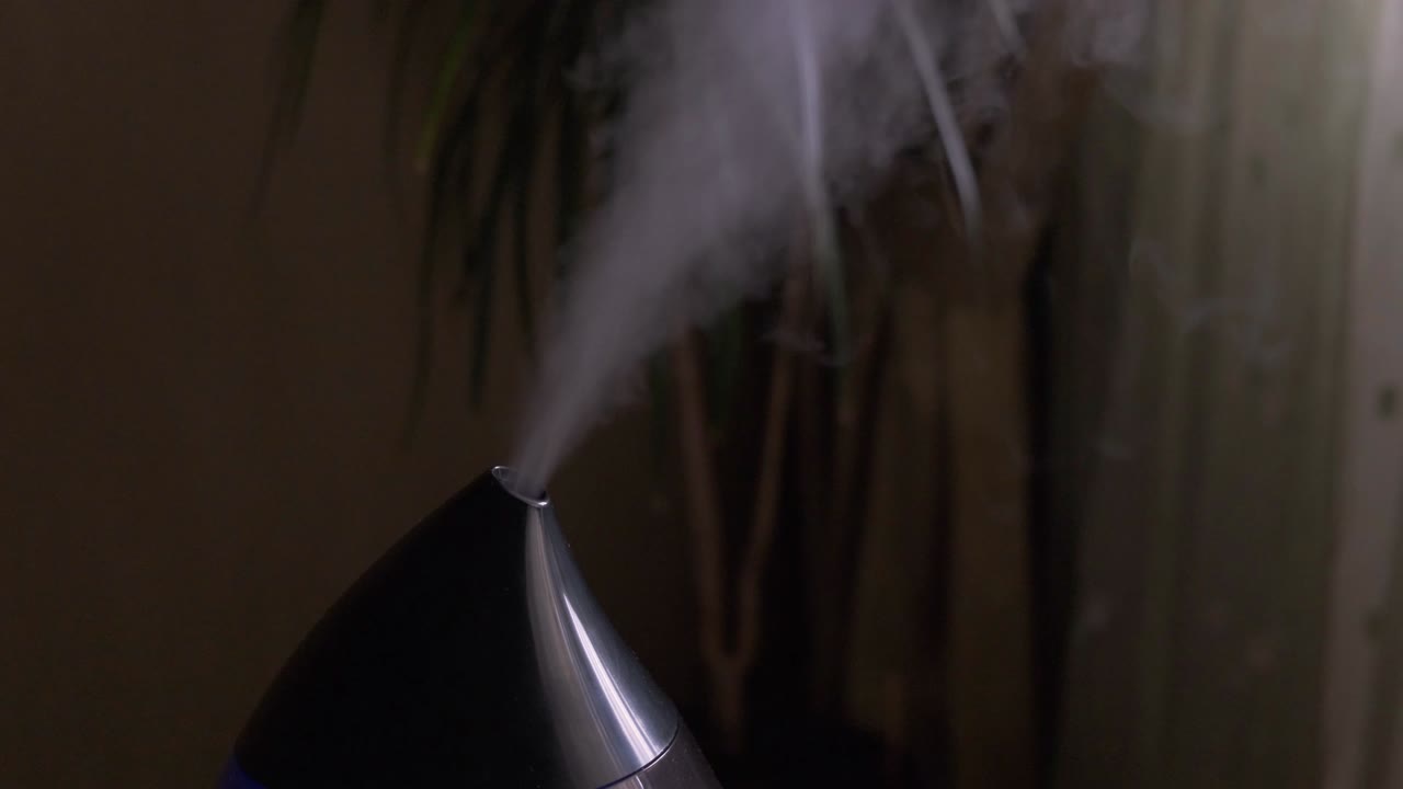 어두운 방에서 현대적인 공기 습기화 장치에서 증기가 나옵니다.