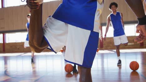 Diverse-male-basketball-team-wearing-blue-sportswear-and-stretching