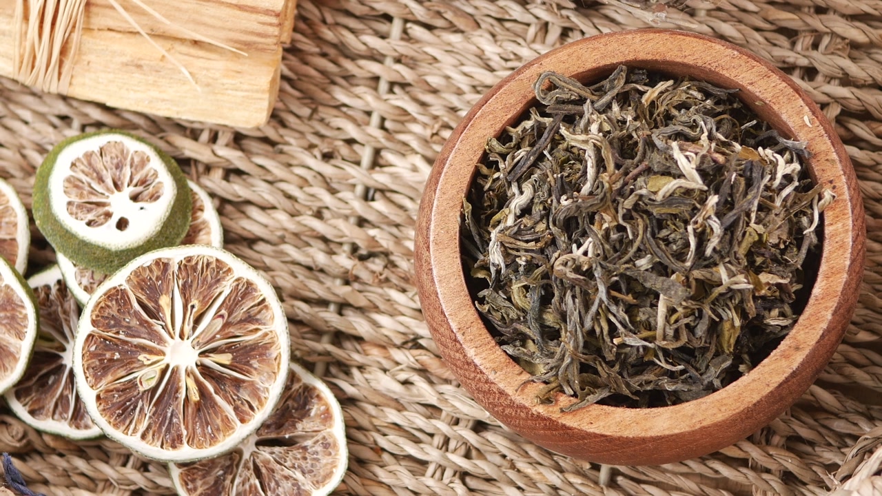 Dried Green Tea Leaves in Wooden Bowl with Dried Limes and Palo Santo