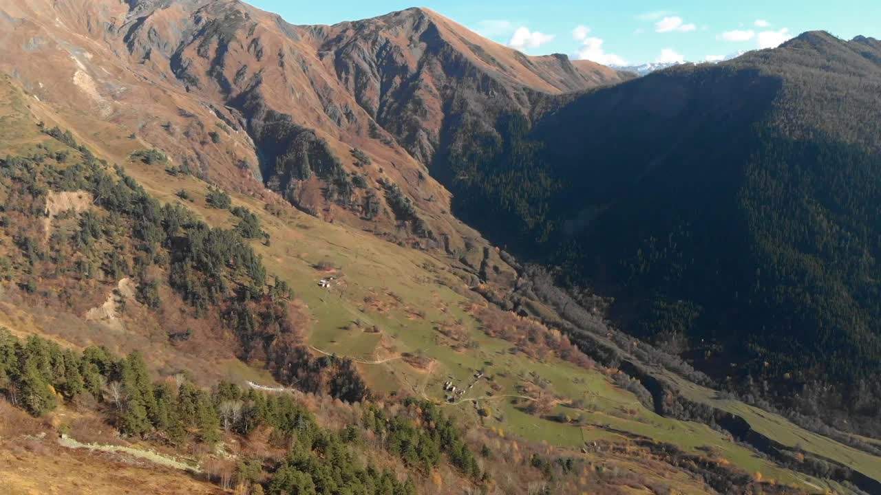 volando a través de las montañas mirando hacia un valle verde con ganado y árboles en un día soleado