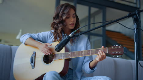 mujer tocando guitarra acústica en un estudio de grabación en casa