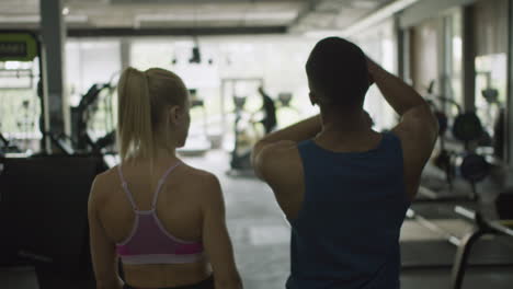 Vista-Trasera-De-Una-Monitora-Caucásica-Y-Un-Atlético-Afroamericano-En-El-Gimnasio.