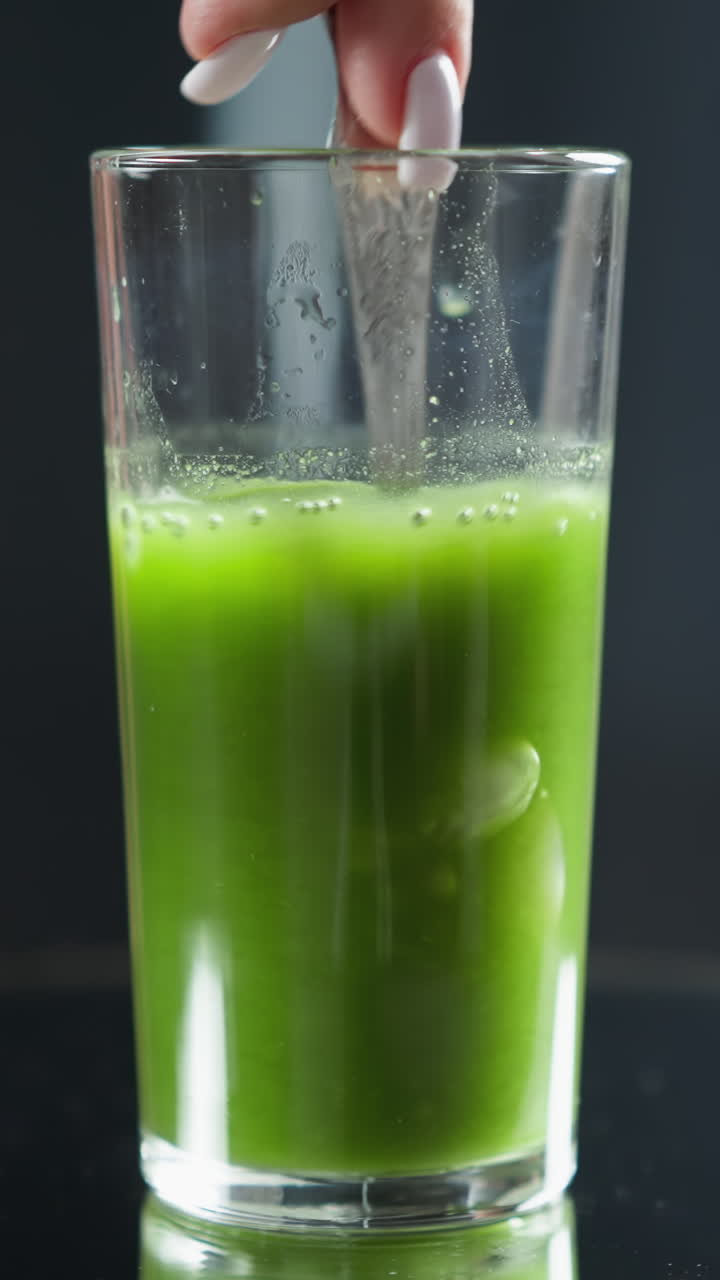 물이 유리잔에 여 녹색 주스가 거품과 부드러운 소용돌이를 만니다.