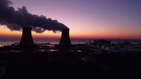 static shot - aerial drone footage of a nuclear power plant cooling towers are sunrise with steam winter