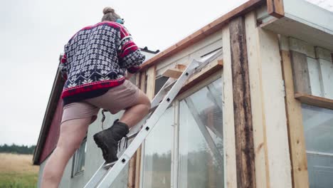 man on ladder building the greenhouse in the farm