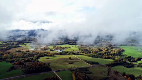 Aerial-view-through-thin-clouds-of-green-meadows-in-remote-countryside