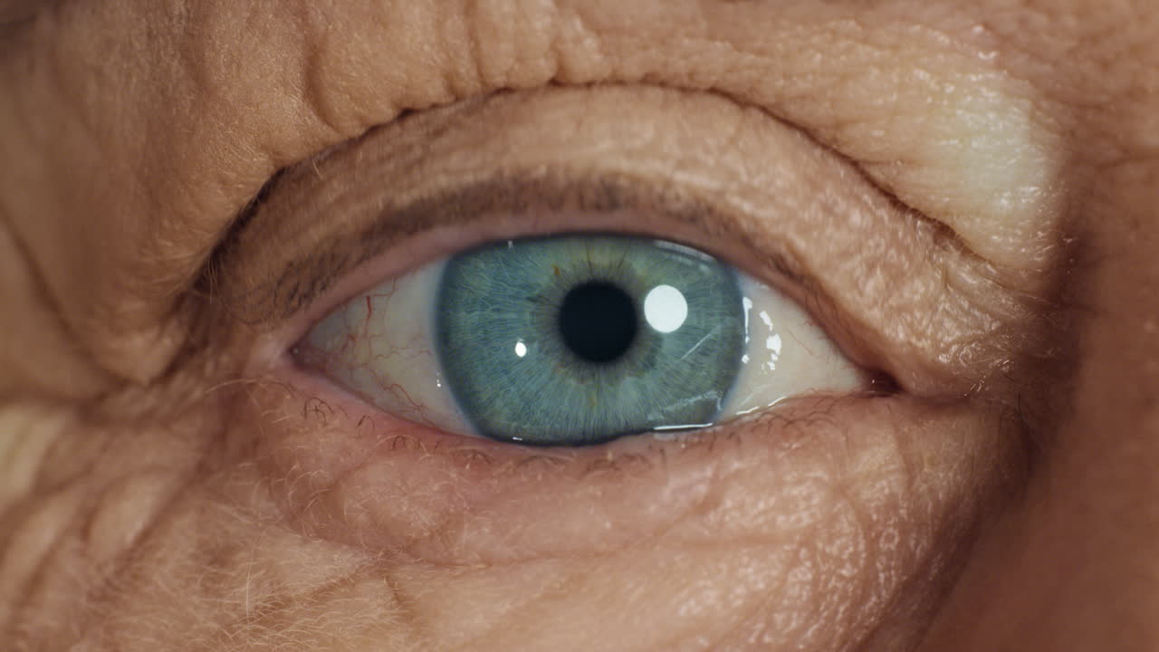 ojo azul de cerca abriéndose mujer vieja parpadeando macro envejecimiento belleza concepto de optometría