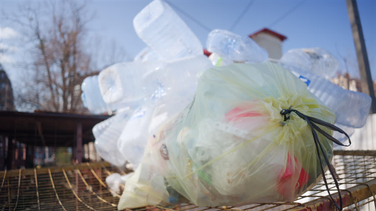 Plastic bottles and a garbage bag on a metal surface outdoors, representing pollution and recycling issues