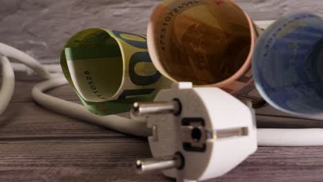 closeup shot of money and a socket showing the high electricity price concept.