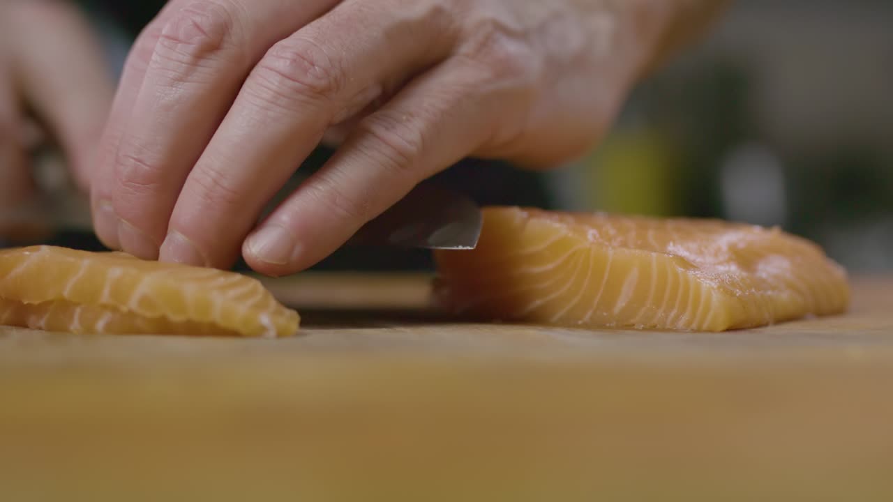 Close up Chef´s hand, slice the raw Salmon fish in wooden board, Depth of field