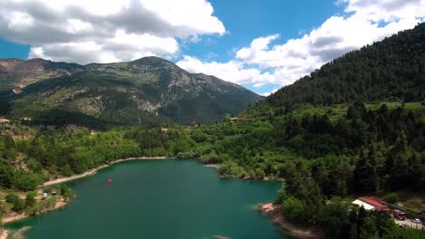 Toma-Aérea-Derecha-Deslizante-De-La-Vista-Del-Lago-Tsivlou-Desde-Arriba-Con-Montañas-Verdes-Que-Rodean-Pacíficamente-Las-Aguas-Naturales-En-Un-Día-Nublado-Y-Nublado