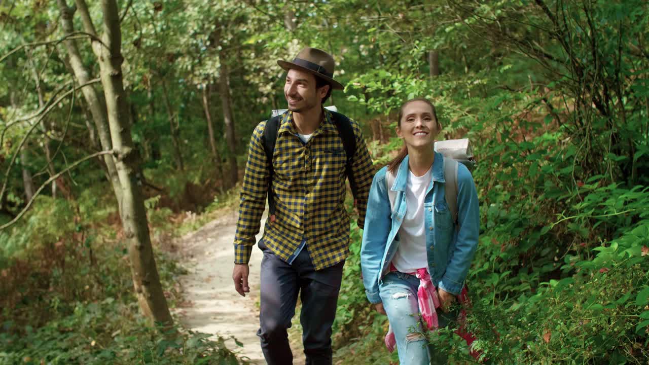 Vista frontale di escursionisti con zaino che camminano nel bosco
