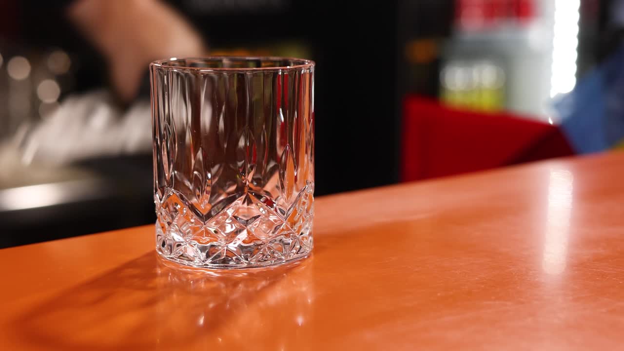el camarero vertiendo hielo en un vaso.