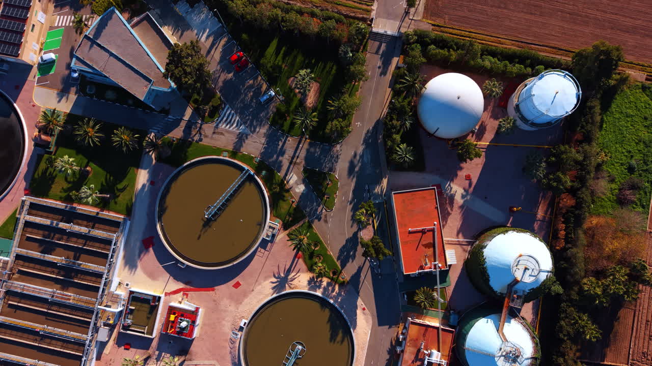 Aerial top down view of circular tanks and silos. Vertical top view of wastewater treatment facility with circular sedimentation pools and white storage silos