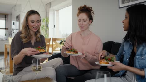 delicious pizza eaten by three caucasian female friends at home.