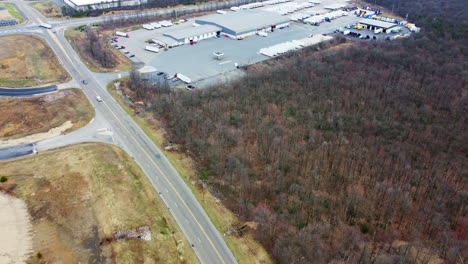 A steady drone push-in on a Schuylkill County warehouse and shipping center, framed by winter trees and a busy rural road. Trucks, containers, and bare branches paint a vivid industrial winter scene.