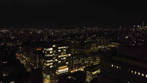 drone shot flying past the riverside church and over the illuminated manhattan cityscape, nighttime in ny, usa