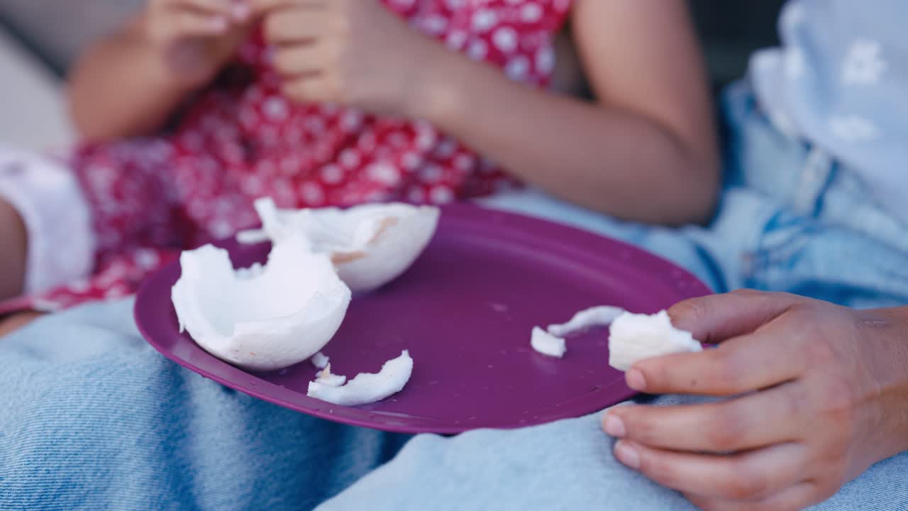 Primo piano di mani che mangiano pezzi di cocco fresco da un piatto