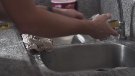 persona manos en espuma lava taza de café y cucharones en la cocina de la casa