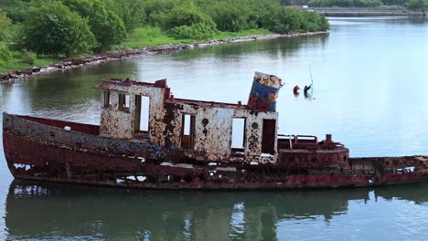 shipwreck with fishermen catching fish in the background in neiba bay, barahona, dominican republic