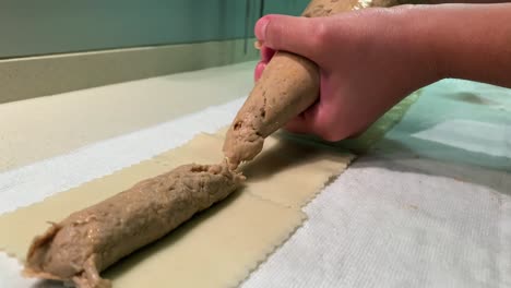 young woman preparing handmade cannelloni. stuffing cannelloni in a white kitchen. cooking some fresh pasta.
