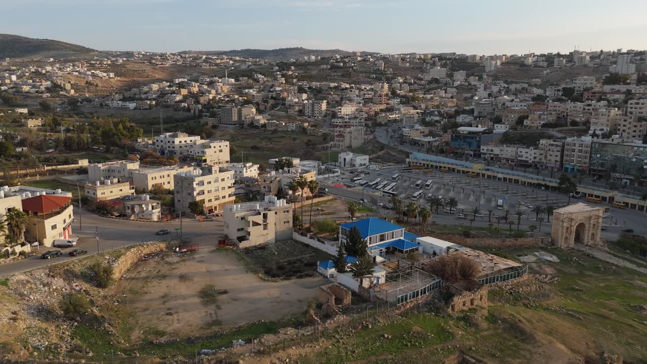 Mozzafiato prospettiva aerea della città greco-romana di Jerash all'alba, che evidenzia la ben conservata Piazza Ovale e le sue colonne circostanti illuminate dalla luce del mattino.