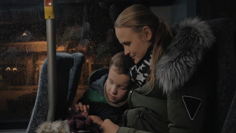 mom and kid playing on mobile during evening bus ride