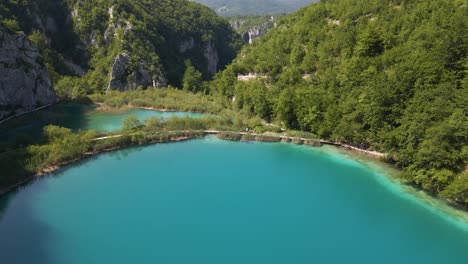 View-of-the-beautiful-Plitvice-Lakes-National-Park-with-many-green-plants-and-beautiful-lakes-and-the-road-that-separates-these-lakes,-along-which-people-walk