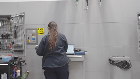 young female apprentice mechanic completing documentation at workbench