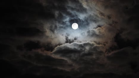 timelapse of static full moon behind fast swirling clouds, copy space