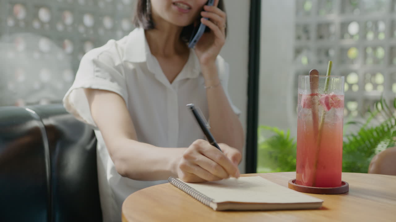 Businessman Taking Notes during Phone Talk in Cafe