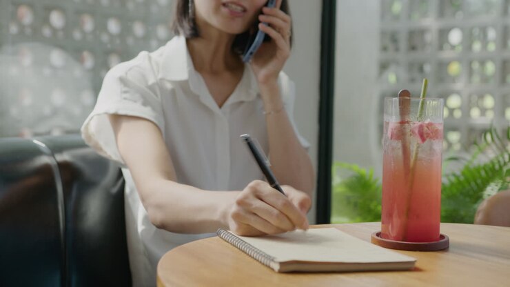 Businessman Taking Notes during Phone Talk in Cafe