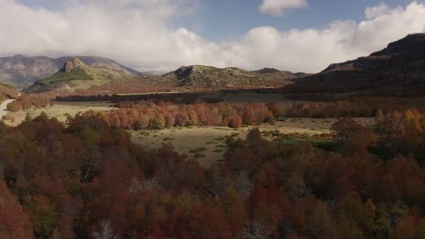 Aerial-shot-of-a-mountain-valley-with-autumnal-woods-in-Patagonia,-Argentina