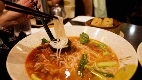 person enjoying chinese noodles with chopsticks