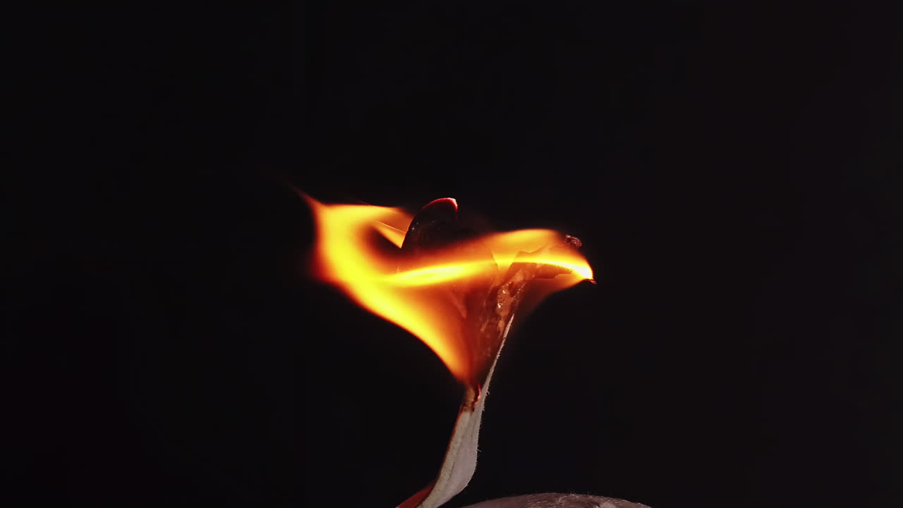 Wax on the stick burning in front of a black background. Ecology idea. Close up. Slow motion shot