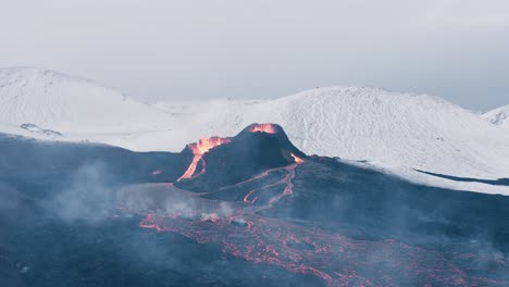 fagradalsfjall eruption in iceland with snow covered mountains in background